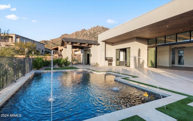 view of pool with a patio area, pool water feature, and an outdoor kitchen