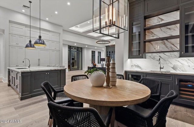 dining space with indoor wet bar, beverage cooler, and light hardwood / wood-style flooring