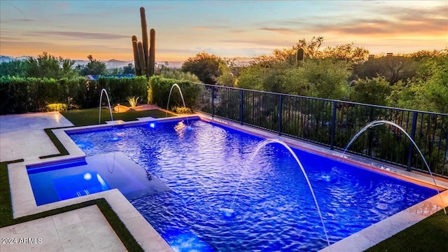 pool at dusk with pool water feature and a jacuzzi