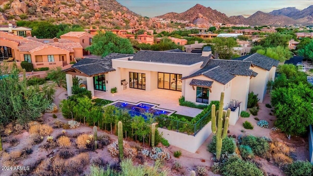 back of property with a mountain view and a patio