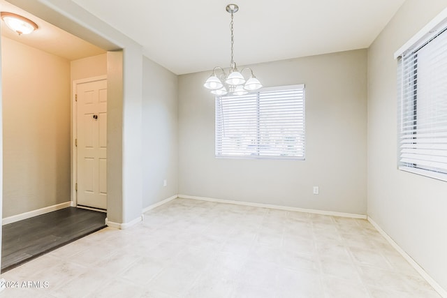 empty room featuring light hardwood / wood-style flooring and a notable chandelier