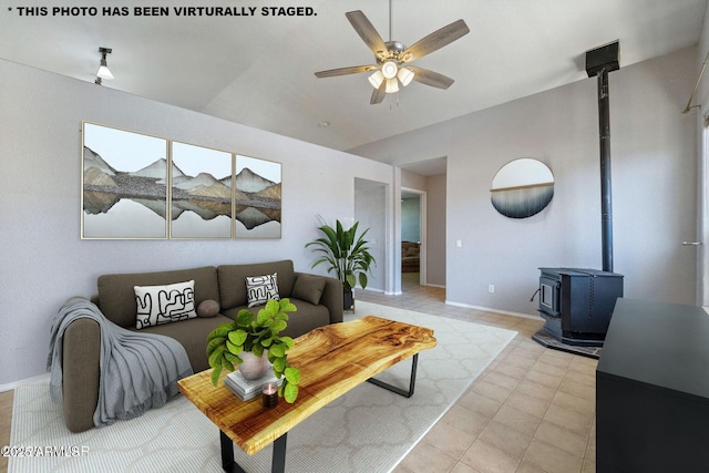 living area with a wood stove, baseboards, vaulted ceiling, and a ceiling fan