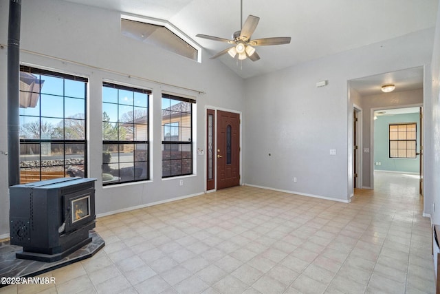 entrance foyer featuring high vaulted ceiling, a wood stove, ceiling fan, and baseboards