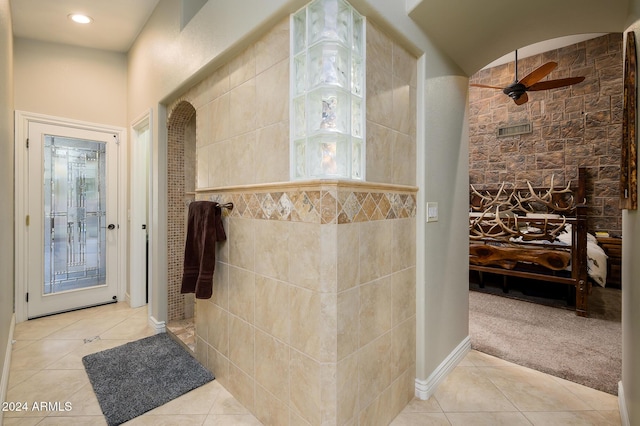 bathroom with tile patterned flooring, a tile shower, ceiling fan, and tile walls