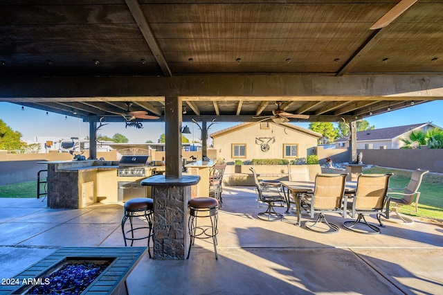 view of patio featuring exterior bar, grilling area, ceiling fan, and exterior kitchen