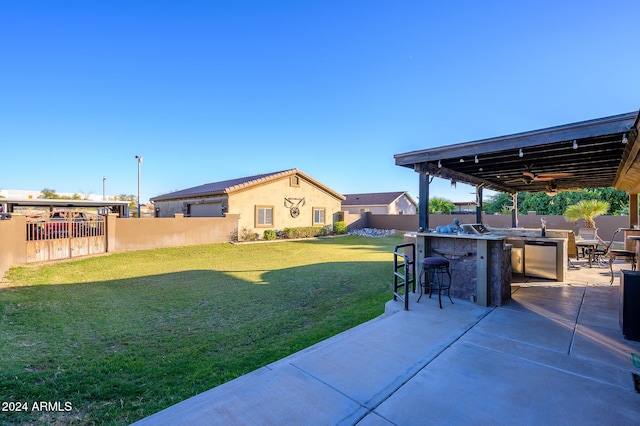 view of yard with exterior bar, a patio, and ceiling fan