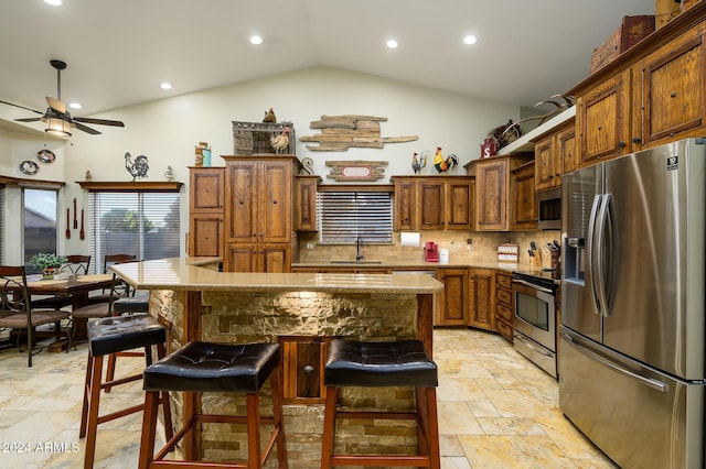 kitchen with appliances with stainless steel finishes, a breakfast bar, sink, a center island, and lofted ceiling