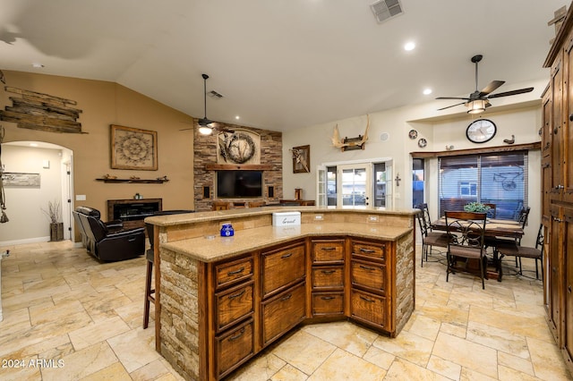 5701 N 105th Ln, Glendale, AZ 85307 - kitchen featuring ceiling fan, open floor plan, stone tile flooring, a fireplace, and vaulted ceiling