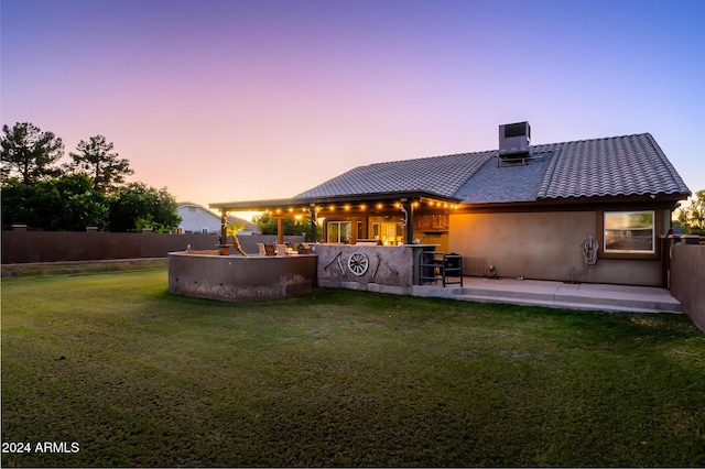 back house at dusk featuring an outdoor bar, a patio, a yard, and central AC