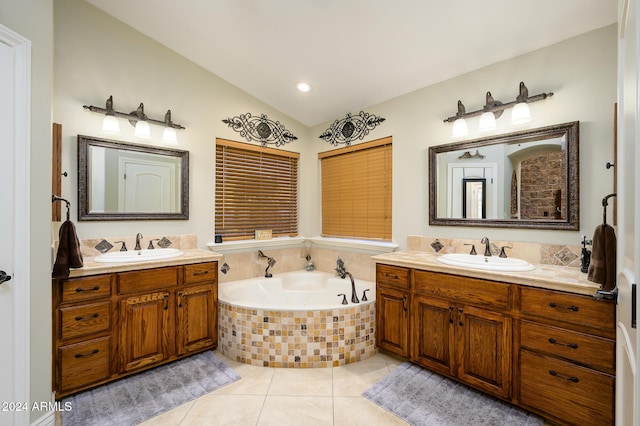 bathroom with tile patterned flooring, vanity, tiled bath, and vaulted ceiling