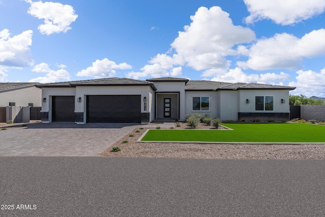 view of front of property with a front lawn, decorative driveway, fence, and an attached garage