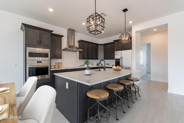 kitchen featuring stainless steel appliances, light countertops, visible vents, dark brown cabinetry, and wall chimney range hood