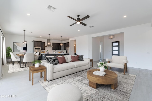 living area featuring baseboards, ceiling fan with notable chandelier, visible vents, and recessed lighting