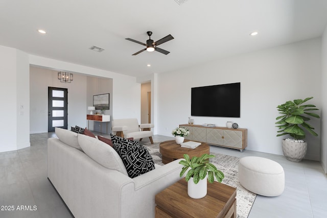 living room with ceiling fan with notable chandelier, visible vents, baseboards, and recessed lighting