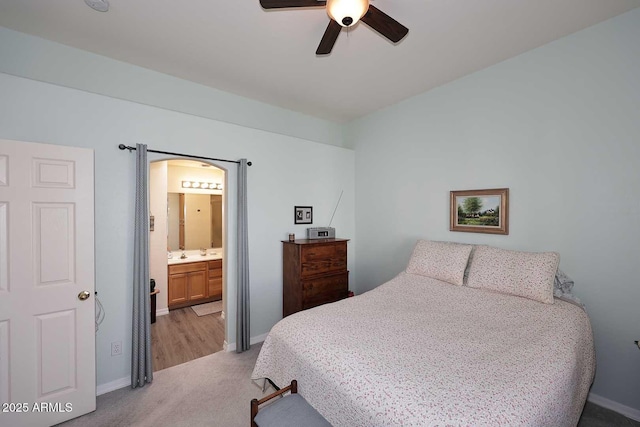 bedroom with baseboards, ensuite bathroom, a ceiling fan, and light colored carpet