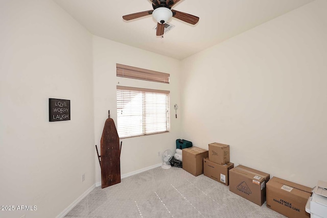 interior space featuring ceiling fan, baseboards, and light colored carpet