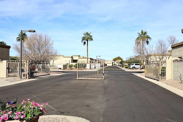 view of road featuring curbs, a gated entry, a residential view, and a gate