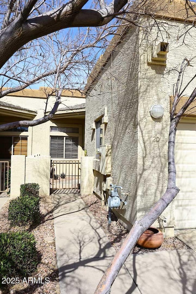 view of property exterior with a fenced front yard, a gate, and stucco siding