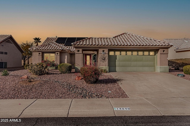 view of front of property with a garage, central AC unit, and solar panels