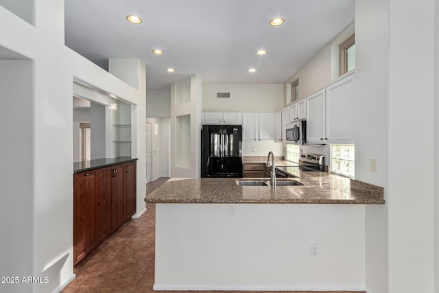 kitchen with kitchen peninsula, appliances with stainless steel finishes, sink, white cabinetry, and dark stone countertops