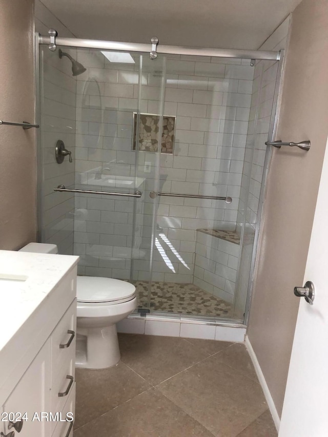 bathroom featuring toilet, tile patterned flooring, vanity, and walk in shower