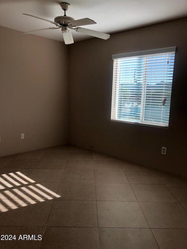 tiled empty room featuring ceiling fan