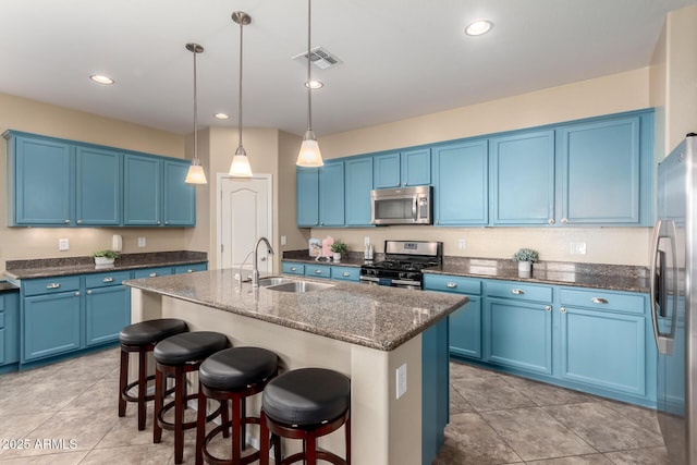 kitchen with appliances with stainless steel finishes, a sink, blue cabinetry, a breakfast bar area, and an island with sink