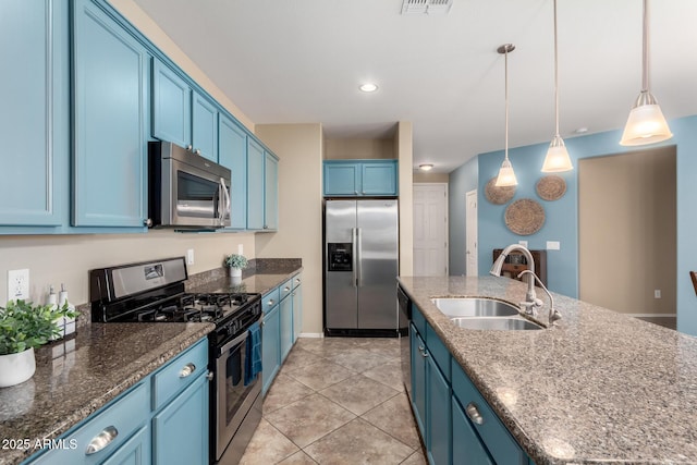 kitchen with stainless steel appliances, blue cabinetry, a sink, an island with sink, and decorative light fixtures