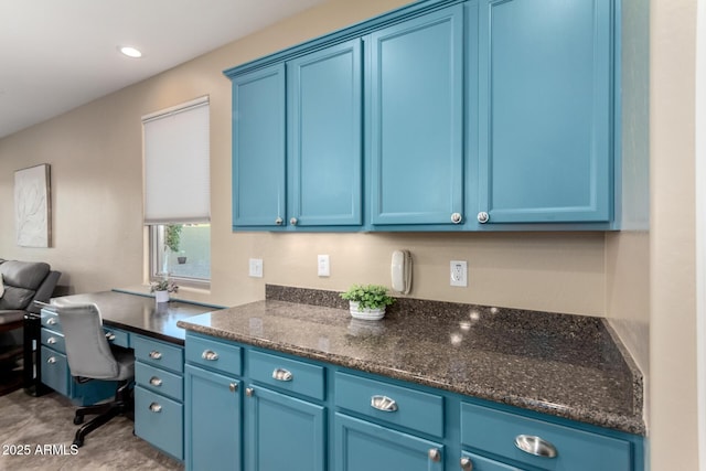 kitchen featuring blue cabinetry, recessed lighting, and dark stone counters