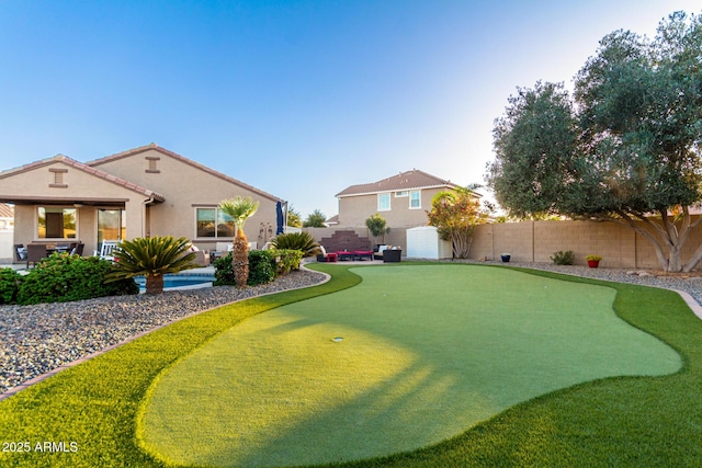 fenced backyard with an area to practice putting