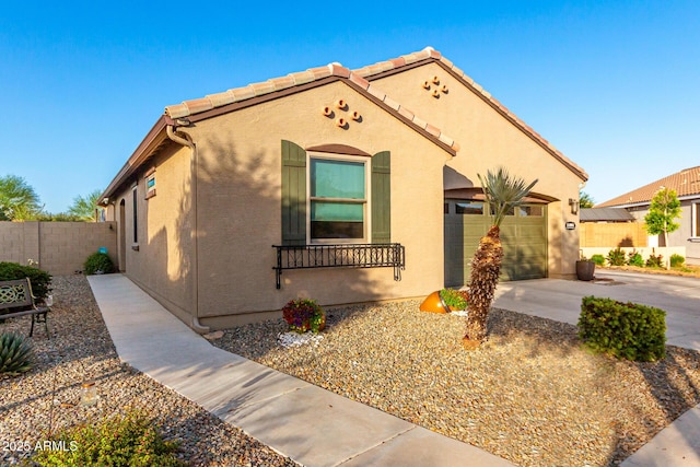 view of front of property with concrete driveway, fence, stucco siding, and a garage