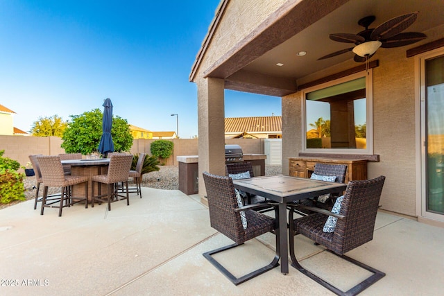 view of patio / terrace with an outdoor kitchen, outdoor dining area, a fenced backyard, and a ceiling fan