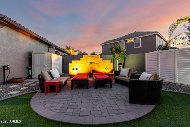 patio terrace at dusk with an outdoor hangout area and a fenced backyard