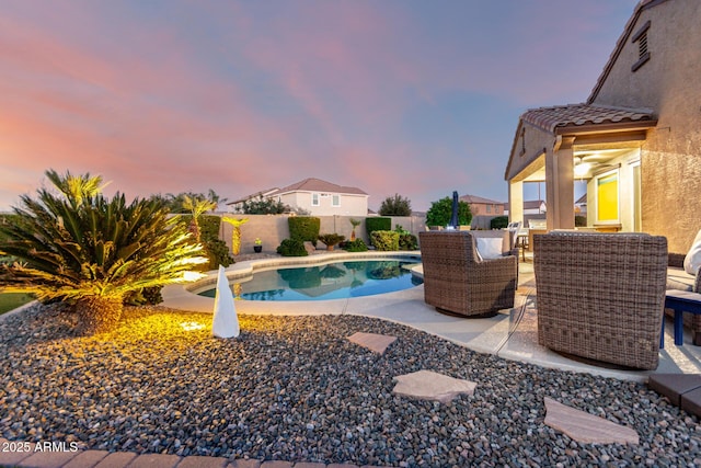 pool at dusk featuring a fenced backyard and a patio