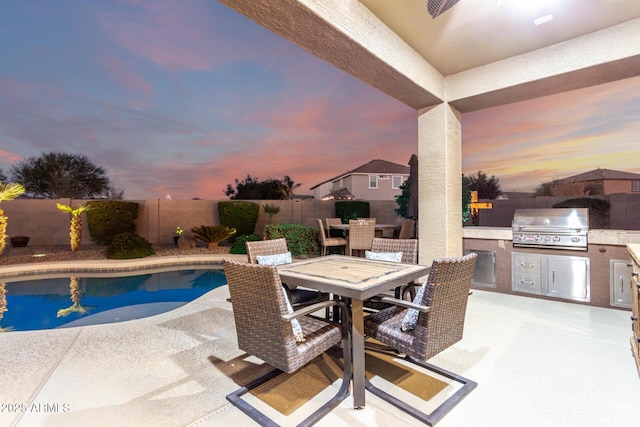 view of pool featuring an outdoor kitchen, a grill, outdoor dining area, a fenced backyard, and a patio