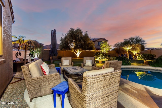 pool at dusk featuring a fenced backyard, a patio area, and an outdoor hangout area