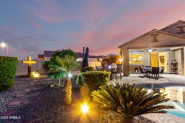 rear view of house with a patio area, exterior kitchen, fence, a tile roof, and stucco siding