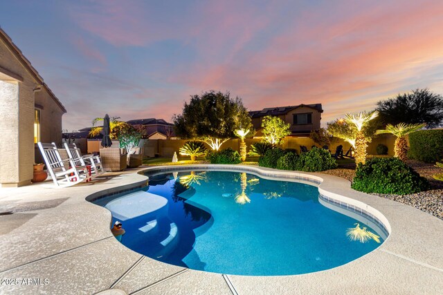 pool at dusk featuring a patio and a fenced backyard