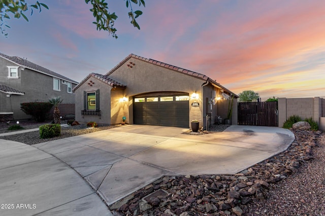 mediterranean / spanish-style house with concrete driveway, stucco siding, fence, a garage, and a tiled roof
