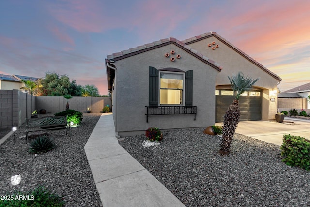 mediterranean / spanish house featuring concrete driveway, fence, an attached garage, stucco siding, and a tile roof