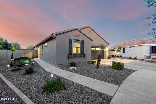 mediterranean / spanish-style home with concrete driveway, fence, a garage, a tile roof, and stucco siding