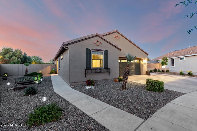 mediterranean / spanish-style house featuring concrete driveway, fence, an attached garage, stucco siding, and a tile roof