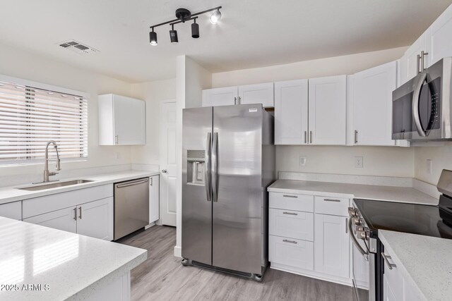 kitchen featuring white cabinetry, appliances with stainless steel finishes, sink, and light hardwood / wood-style flooring