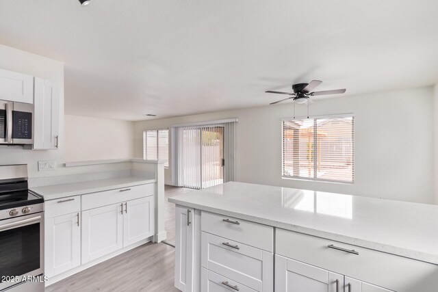 kitchen featuring stainless steel appliances, white cabinetry, a wealth of natural light, and light hardwood / wood-style flooring