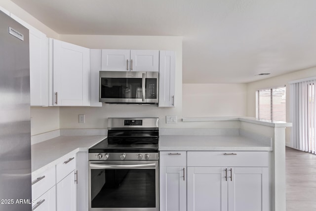 kitchen featuring white cabinetry, appliances with stainless steel finishes, light hardwood / wood-style flooring, and kitchen peninsula