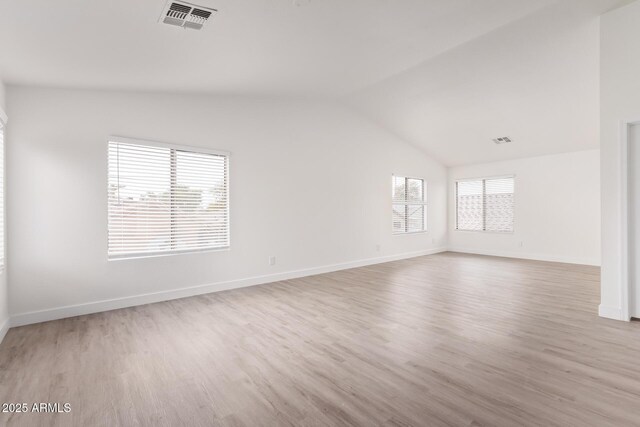 spare room featuring lofted ceiling and light wood-type flooring