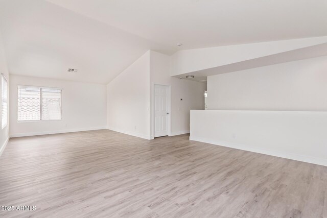 empty room featuring vaulted ceiling and light hardwood / wood-style floors