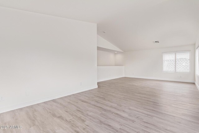 empty room featuring lofted ceiling and light wood-type flooring