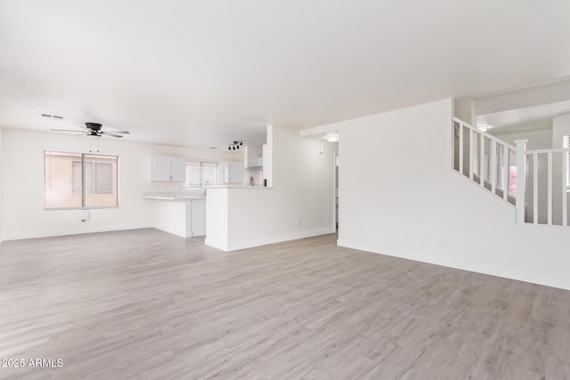 unfurnished living room featuring ceiling fan and light wood-type flooring