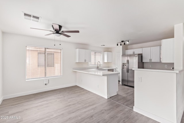 kitchen featuring kitchen peninsula, white cabinetry, sink, stainless steel fridge with ice dispenser, and light wood-type flooring